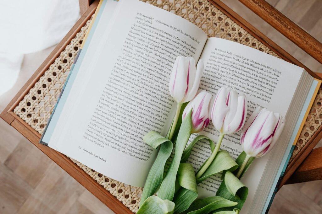 composition of fresh romantic flowers on open book arranged on vintage wicker table at home